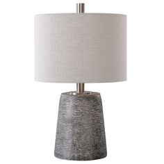 a gray table lamp with a white shade on the base and a light grey drum