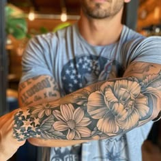 a man with a flower tattoo on his arm and arms is looking at the camera