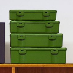 four green storage boxes sitting on top of a wooden shelf next to a purple box