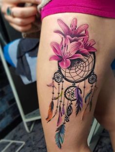 a woman's thigh with a flower and dream catcher tattoo on the side of her leg