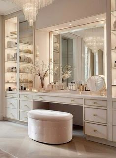 a white vanity with a large mirror and chandelier hanging from it's ceiling