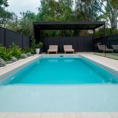 an empty swimming pool with two lounge chairs next to it