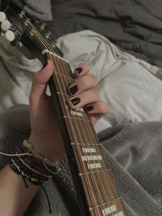 a woman with black nail polish holding an electric guitar