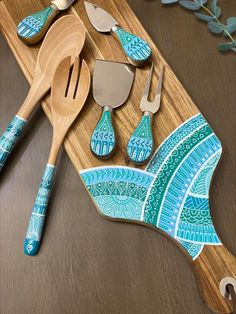 wooden utensils and spoons are sitting on a cutting board with blue designs