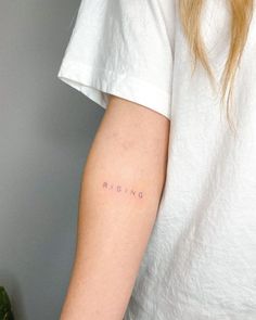 a woman's arm with the word rising tattooed on it