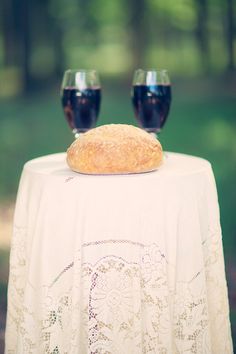 two wine glasses sitting on top of a table with a loaf of bread on it