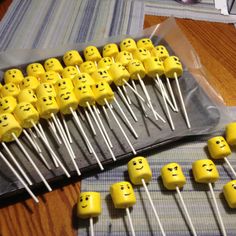 many yellow marshmallows with faces on them sitting on a table next to some forks