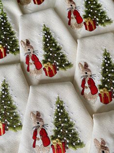 several napkins with embroidered images of rabbits and christmas trees