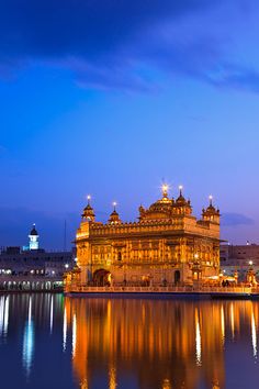 the golden building is reflected in the water at night, with lights reflecting off it's sides