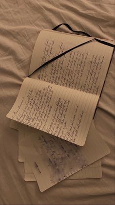 three sheets of paper with writing on them sitting on a bed sheet covered in white sheets