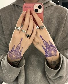 a woman with tattoos holding her phone up to her face and looking at the camera