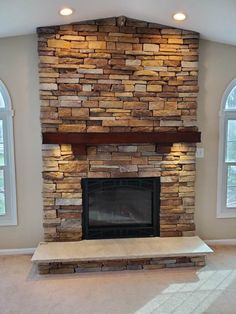 a living room with a stone fireplace and arched windows