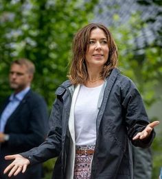 a woman standing in the middle of a forest with her hands out and two other people behind her