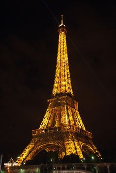 the eiffel tower lit up at night with lights on it's sides