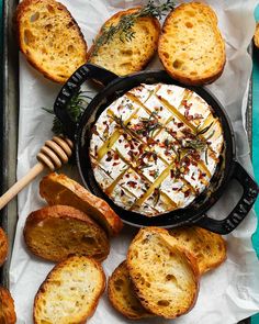 a pan filled with bread and cheese on top of a blue table cloth next to other baked goods