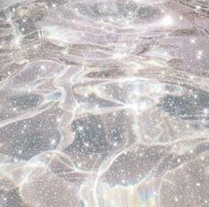 an image of some water and stars in the sky with white sparkles on it