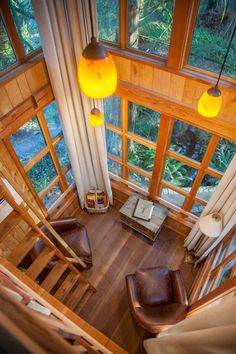 an aerial view of a living room with wooden floors and windows, looking down at the stairs