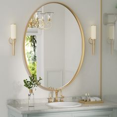 a bathroom with a large round mirror above the sink and a gold faucet