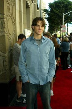 a young man standing in front of a red carpet