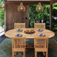 a wooden table with four chairs and plates on it in front of an open door