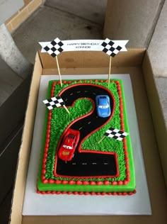 a birthday cake in the shape of a number 2 with a car on it and two candles