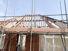 a house under construction with scaffolding on the roof and windows being framed by metal bars