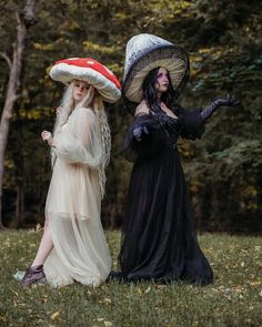 two women dressed up in costumes and hats standing next to each other on the grass