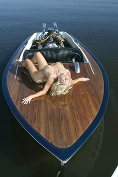 a woman laying on top of a wooden boat