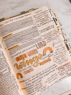 an open bible with handwritten words on the pages and in front of a marble countertop