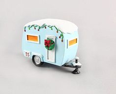 a small toy trailer with christmas decorations on the front and side doors, sitting on a gray surface