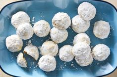 a blue bowl filled with snowball cookies on top of a table