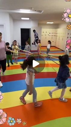 children are playing in an indoor play area with colorful carpet and flowers on the walls