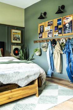 a bed room with a neatly made bed and lots of pictures on the wall above it