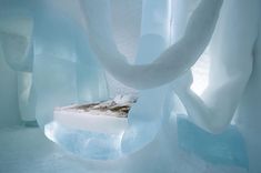 a bed made out of ice is in the middle of an icy room with white curtains