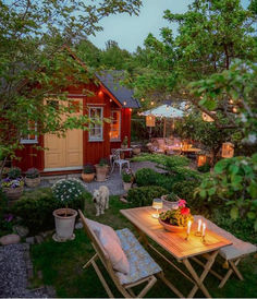 a table with candles on it sitting in the middle of a yard next to a shed