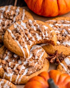 several cookies with white icing and pumpkins in the background