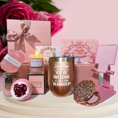 a pink box filled with lots of different items next to a candle and some flowers