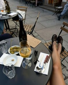 a person's legs resting on a table with food and wine in front of them