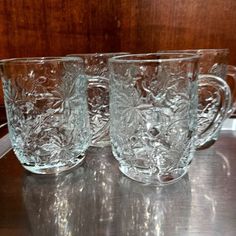 three glass mugs sitting on top of a metal table