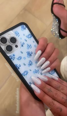 a woman holding up her phone case with white and blue flowers on the cover,