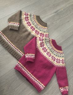 two sweaters sitting on top of a wooden floor next to each other and one is pink