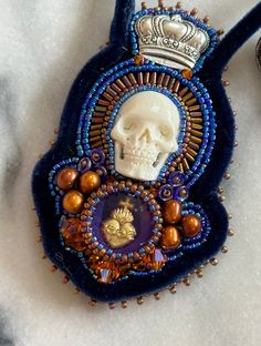 a blue purse with a skull and crown on it's back, sitting on a white surface