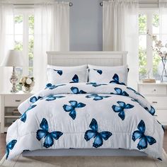 a bed with blue butterflies on it in a room next to two lamps and windows