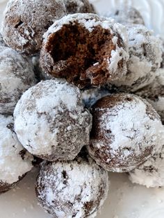 a pile of powdered sugar donuts sitting on top of a white plate