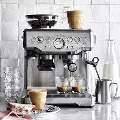 an espresso machine sitting on top of a counter next to plates of pastries