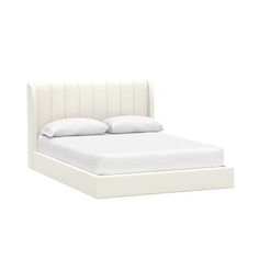 a white bed with two pillows on top of it and a night stand next to it