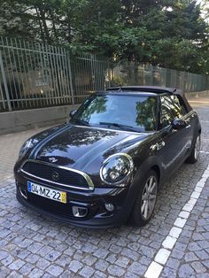 a small black car parked in front of a fence