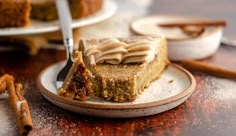 a piece of cake sitting on top of a white plate next to cinnamon stick sticks