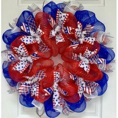 a red, white and blue mesh wreath on a front door with the american flag