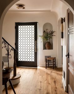 an entry way with a black door and wooden floors